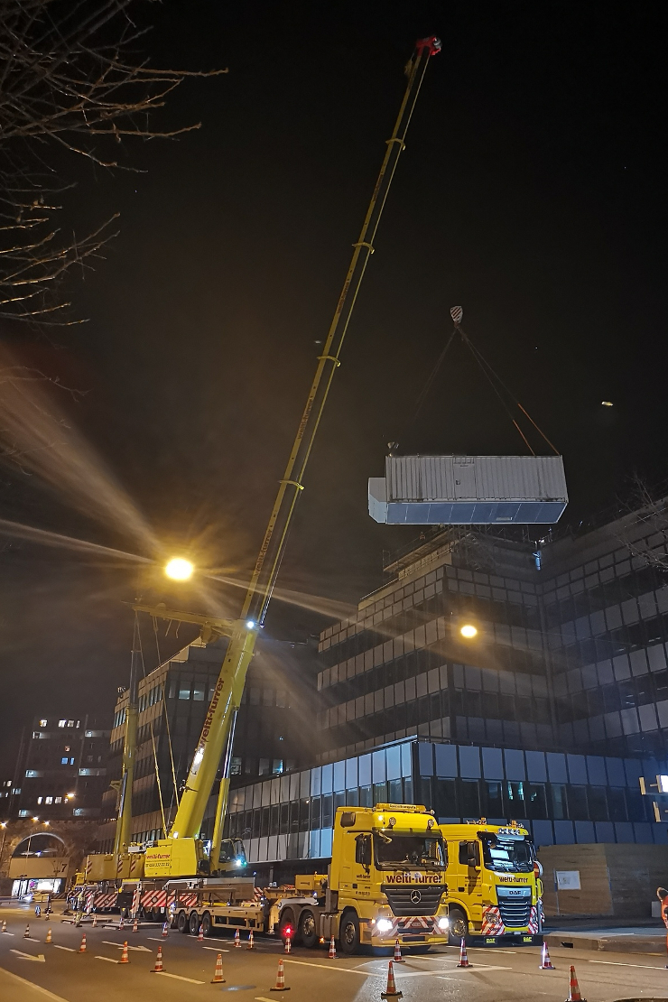 Heben der Notstromgruppe mit dem Mobilkran an ihren neuen Standort auf dem Gebäude der Zürcher Kantonalbank